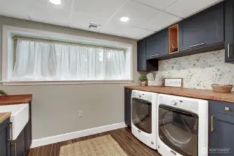 Spacious laundry room with farmhouse utility sink & storage cabinets.