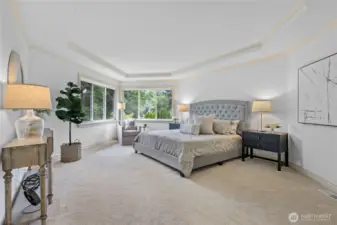 Serene primary suite with tray ceiling and peaceful greenbelt views.