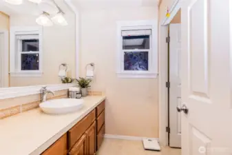 A spacious upper-level bathroom featuring a long vanity with vessel sink, large framed mirror, neutral tilework, and abundant counter space. Designed for both style and everyday convenience.