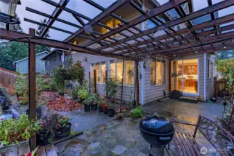 A private outdoor retreat featuring an expansive pergola structure, stone patio, and lush garden areas. This versatile space is perfect for outdoor dining, quiet mornings, and year-round enjoyment, with seamless indoor–outdoor flow from the kitchen.