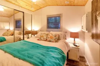 Primary bedroom with full bed, nightstands, and warm finishes