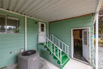 Rear entrance to the home - note the heat pump for year-round comfort, and the entrance to the storage/workshop