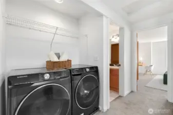 Dedicated laundry area with full-size washer and dryer and additional shelving for storage.