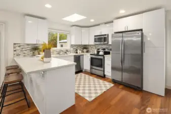 The updated kitchen pairs clean, timeless design with modern utility, featuring designer cabinetry, white quartz countertops, custom backsplash, and stainless steel appliances.