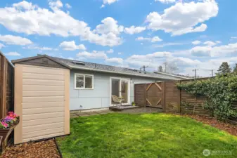 Just off the kitchen and dining area, a small yard offers room for pets, gardening, or casual outdoor entertaining, while the fully fenced oversized courtyard creates another inviting layer of privacy and function. A backyard shed neatly houses garden tools and outdoor gear, reinforcing the home’s blend of charm and usefulness.