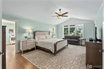 The spacious primary suite features vaulted ceilings, white Oak hardwood floors, ceiling fan, and a sitting room/office/exercise room.