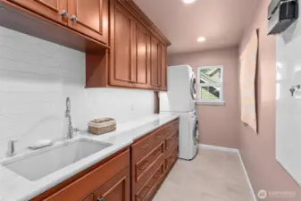Spacious utility room is appointed with solid Cherry cabinets, porcelain tile floor, Quartzite countertops, Subway tile backsplash, sink and W/D included.