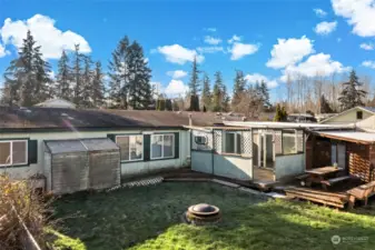 Backside of house with firepit and storage space off the house