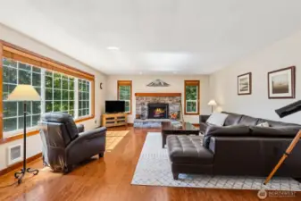 Large living room has plenty of natural lighting, hardwood floors, and a wood fireplace.