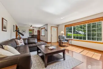 Looking back from living room to the front entry and dining room -- lots of natural lighting, hardwood floors, and a wood fireplace.
