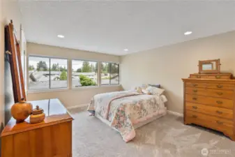 Spacious primary bedroom with lots of windows and recessed lighting.