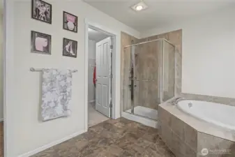 Primary bath view of soaking tub, separate shower and walk-in closet.