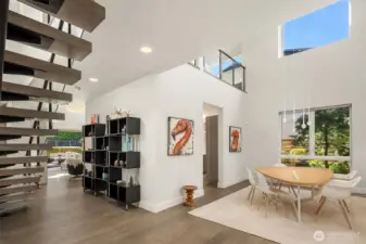 Open architectural lines connect the floating staircase, dining, and living areas in a continuous, light-filled composition.