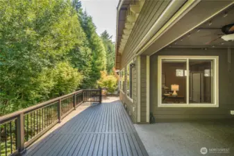 The oversized covered patio with fireplace and motorized screens leads to the freshly painted deck overlooking the permanent greenbelt.