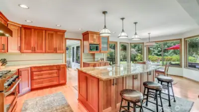 Enjoy meal prep with a view—kitchen overlooks the backyard gardens and evening sunsets. Wall of windows flood the kitchen with light while framing lush landscaping that blossoms year-round. French doors open from the kitchen to the deck, creating the perfect flow for indoor-outdoor living. Gather around the island or step outside—this kitchen blends function with breathtaking backyard views.