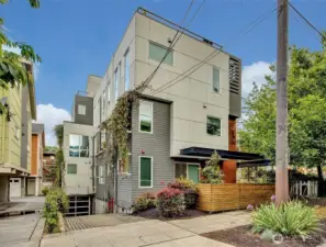 Contemporary townhouse community features modern architecture, lush greenery, and secure garage parking, all tucked into a vibrant urban neighborhood.