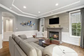 Featuring a gas fireplace , wainscotting, and tray ceiling.