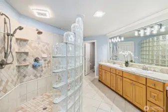 The primary bath is complete with a  custom glass walk-in shower and plenty of counterspace.