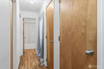 Hallway layout with utility closet (water heater and AC), additional storage closet, and in-unit washer and dryer. Bathroom straight ahead with two bedrooms located to the left.