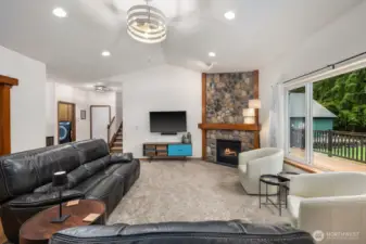 Spacious living area with high ceilings and an open layout connecting toward the entry, stairs, and adjacent living spaces while maintaining views toward the backyard.