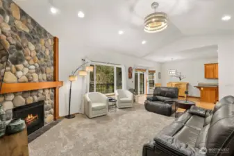 Expansive main living space with vaulted ceilings and a seamless connection toward the dining area and kitchen, creating an open central gathering area.