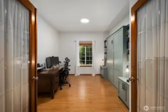 Versatile main-level den with murphy bed, double glass doors and a window overlooking the property, offering space for a home office, study, or creative workspace.