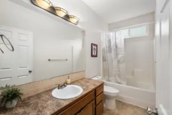 Full bathroom with vanity, large mirror, and tub-shower combination located on the main floor for convenient access from nearby bedrooms and living areas.