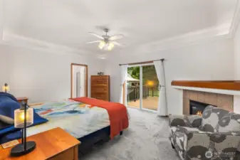Spacious primary bedroom with sliding glass door access to the deck and a private fireplace, creating a comfortable retreat connected to the outdoor living area.