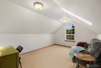 Spacious upstairs recreation room with vaulted ceilings, an arched window, and skylight bringing in natural light. Flexible space for a media room, playroom, or additional living area.