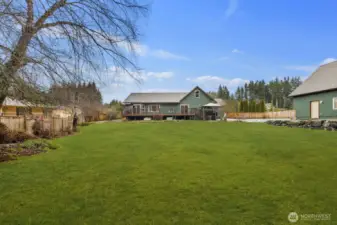 Wide view of the expansive backyard lawn looking toward the home and raised deck, showcasing the large open outdoor space.