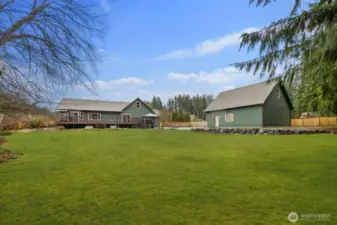 View across the spacious backyard highlighting the detached outbuilding and the home's elevated deck.