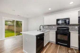 Beautifully updated modern kitchen featuring crisp white cabinetry, matching appliances, recessed lighting, and a thoughtfully designed peninsula for added functionality and style.