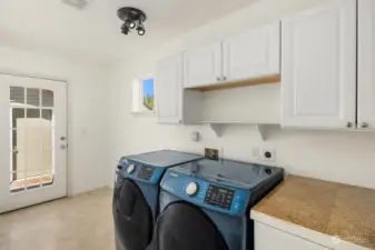 Sizeable laundry room with built-in cabinetry and access to the patio and backyard.