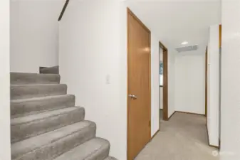 Stairs to 2nd level and 1st floor hallway to den/office and half bath with laundry.