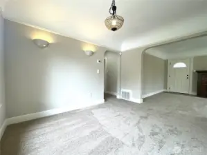 Standing in the corner of the dining room and looking towards the hallway and front door. Features the arched doorways. Updated lighting to keep things modern.  Note the coved ceilings and the crown molding here. Beautiful!