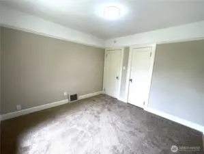 Here is the primary bedroom entry door and closet door and the furnace vent. New carpet, trim, lighting and paint.