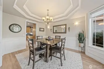Elegant formal dining room with wainscotting, Coffered ceiligns and large windows.