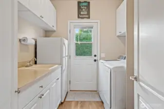 Utility room with mud sink, lots of storage and door leading outside.