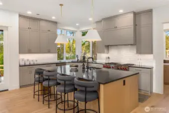 Chefs kitchen features oversized island with quartz slap counter, eating bar, and in island prep sink