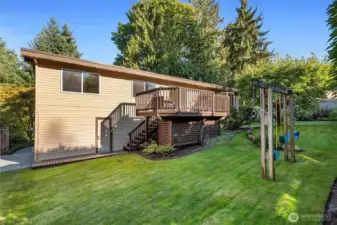 Private sunny backyard with lawn, playset, garden space, and storage shed