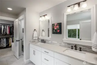 Primary bathroom has quartz countertops and double undermount sinks with custom tile backsplash. Showing private water closet and walk-in closet.