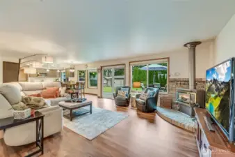 view of family room adjoins kitchen, toasty fireplace & tons of windows