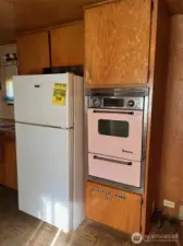 Stove and newer fridge. Fridge located in former laundry hook-up area