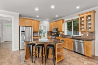 Kitchen with granite counters, tile floors & backsplash, stainless appliances & pantry.