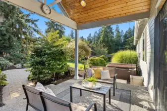 Fully fenced backyard retreat with custom waterfall, covered patio with hot tub, irrigation system, landscape lighting, raspberry & rhubarb plants, and storage shed.