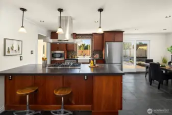 Slab countertops offer both an abundance of prep space, but also space where family and guests can hang out and chat. Industrial style five burner stove and overhead extraction fan is a standout modern feature.