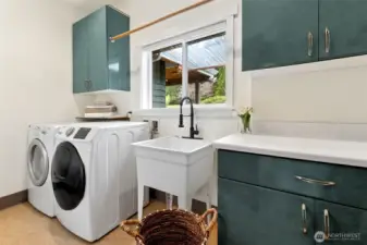 Spacious Main floor laundry with utility sink and generous storage cabinetry/work space.