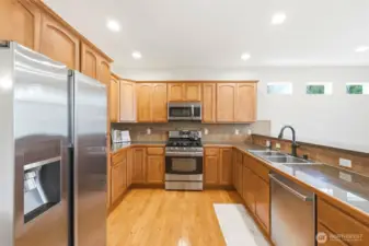 Kitchen featuring gas range, granite counters, and eating bar open to family room