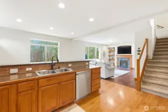 Kitchen eating bar opens to family room with gas fireplace and greenbelt views