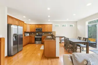 Open-concept kitchen and family room with hardwood floors and greenbelt views